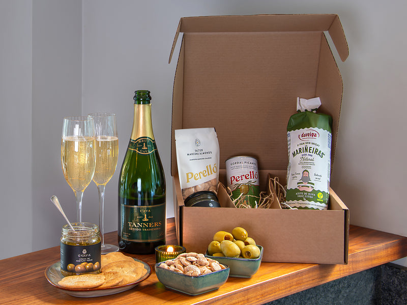 Gourmet gift box with Tanners Cava, snacks, including olives. Displayed on a wooden table.