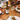 A bottle of Tanners Chardonnay white wine is being poured from a dark glass bottle into a wine glass on a rustic wooden dining table, surrounded by plates, cutlery, a glass vase with autumn leaves, and a hand pouring the wine.