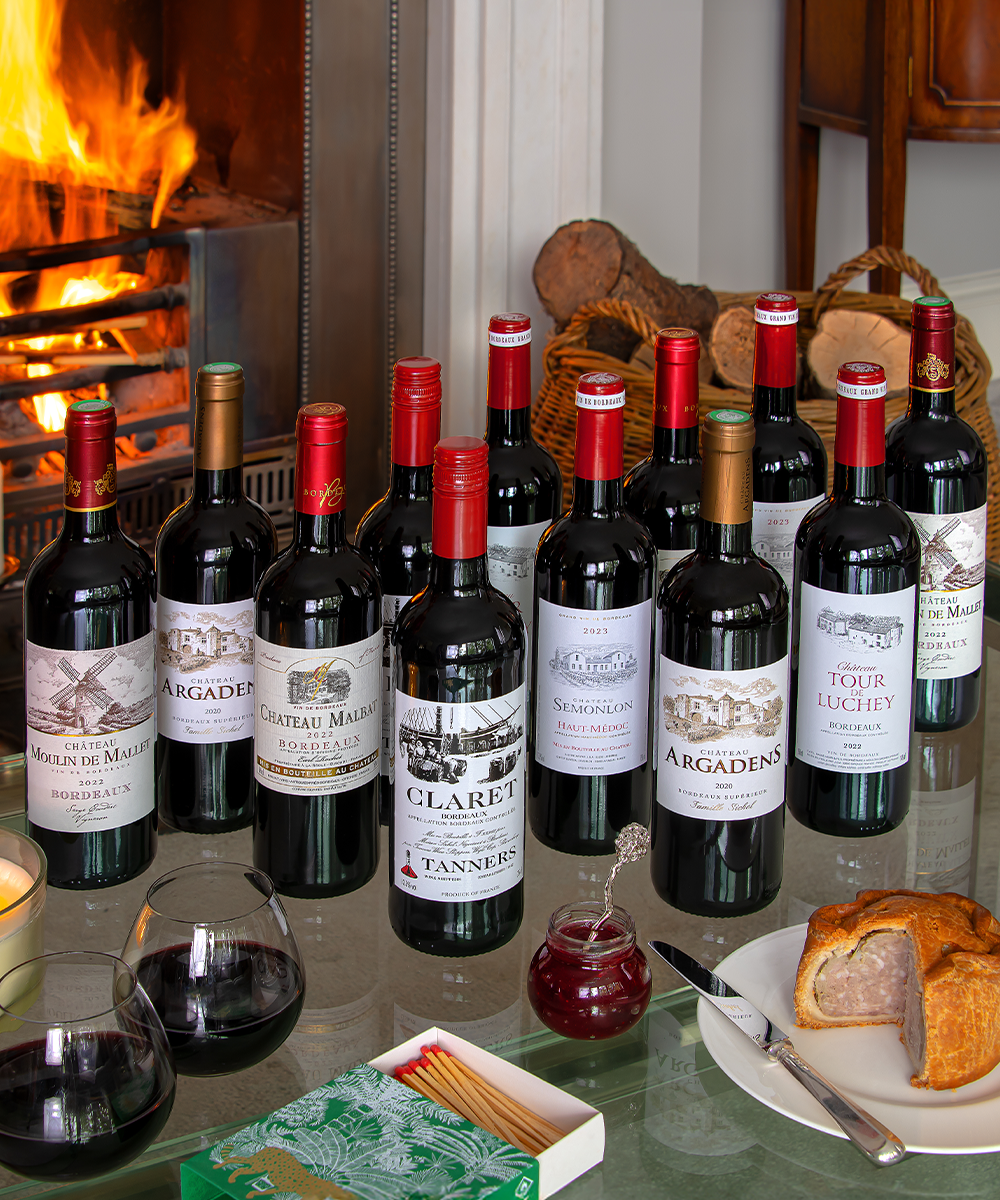 Collection of wine bottles on a table with a fireplace in the background