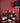 Collection of wine bottles on a table with a red wall and lamp in the background