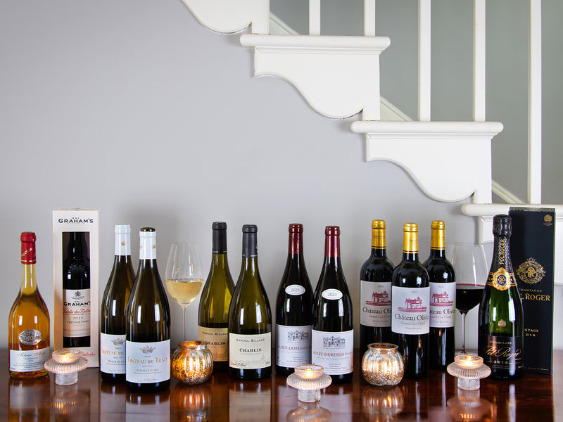 Row of wine bottles on a table with a staircase in the background
