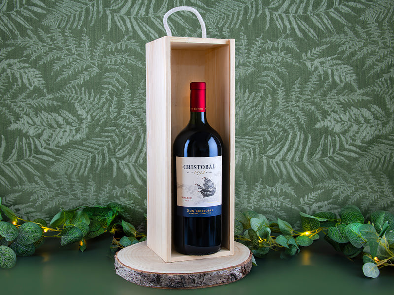 Bottle of Cristobal wine in a wooden box with a green leafy background