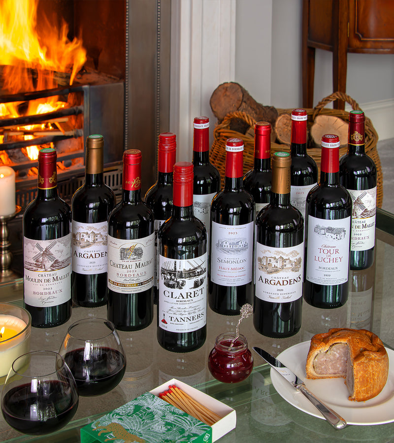 Collection of wine bottles on a table with a fireplace in the background