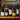 Five wine bottles lined up on a wooden shelf in front of a rustic stone wall. The bottles include wines from Tanners, Laurent Perrier, and Domaine Guerrin & Fils.