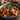 Blue bowl of hearty stew with meat and vegetables on a wooden surface