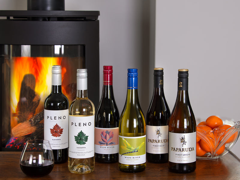 Collection of wine bottles on a table with a fireplace in the background