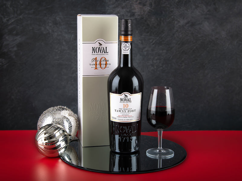 Bottle of Noval 10-year-old Tawny Port with a glass on a dark surface.