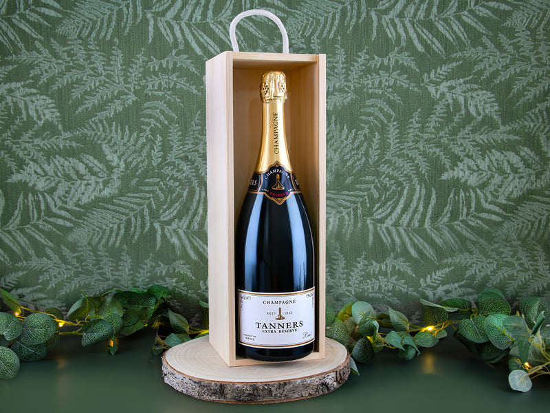 Bottle of Tanners champagne in a wooden box with a green leafy background