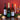 Wine bottles and glasses on a table with candles and greenery against a red background