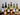 Collection of wine bottles with labels on a reflective surface with candles in the background