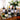 Assorted wine bottles on a mirrored tray with a floral arrangement in the background.