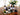 Assorted wine bottles on a mirrored tray with a floral arrangement in the background.