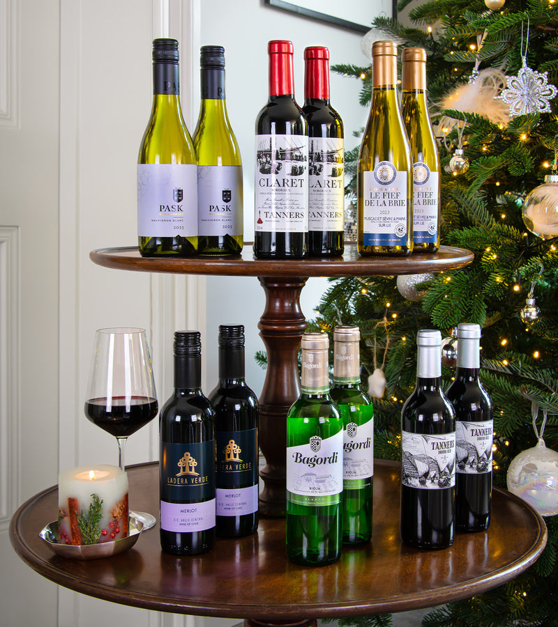 Wine bottles on a wooden stand with a Christmas tree in the background